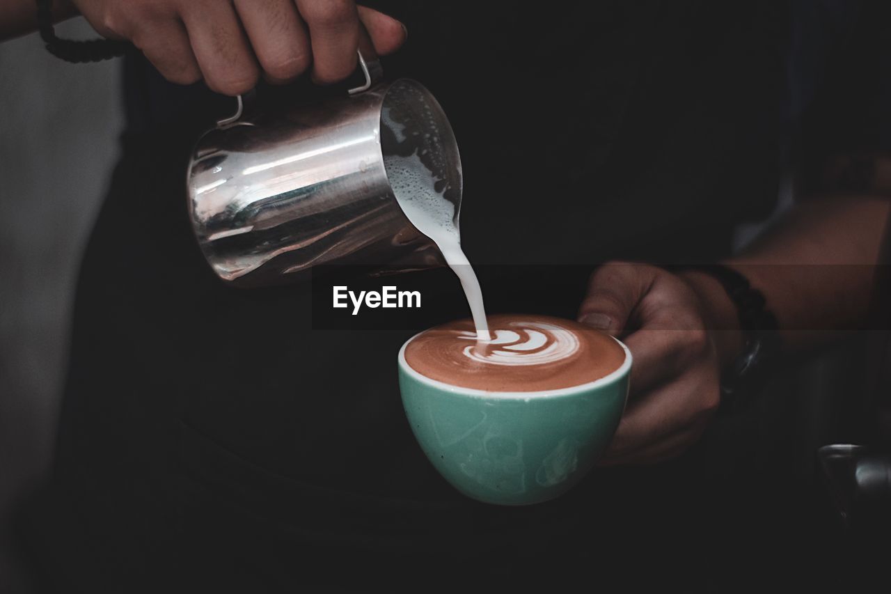 Midsection of man pouring coffee in cup