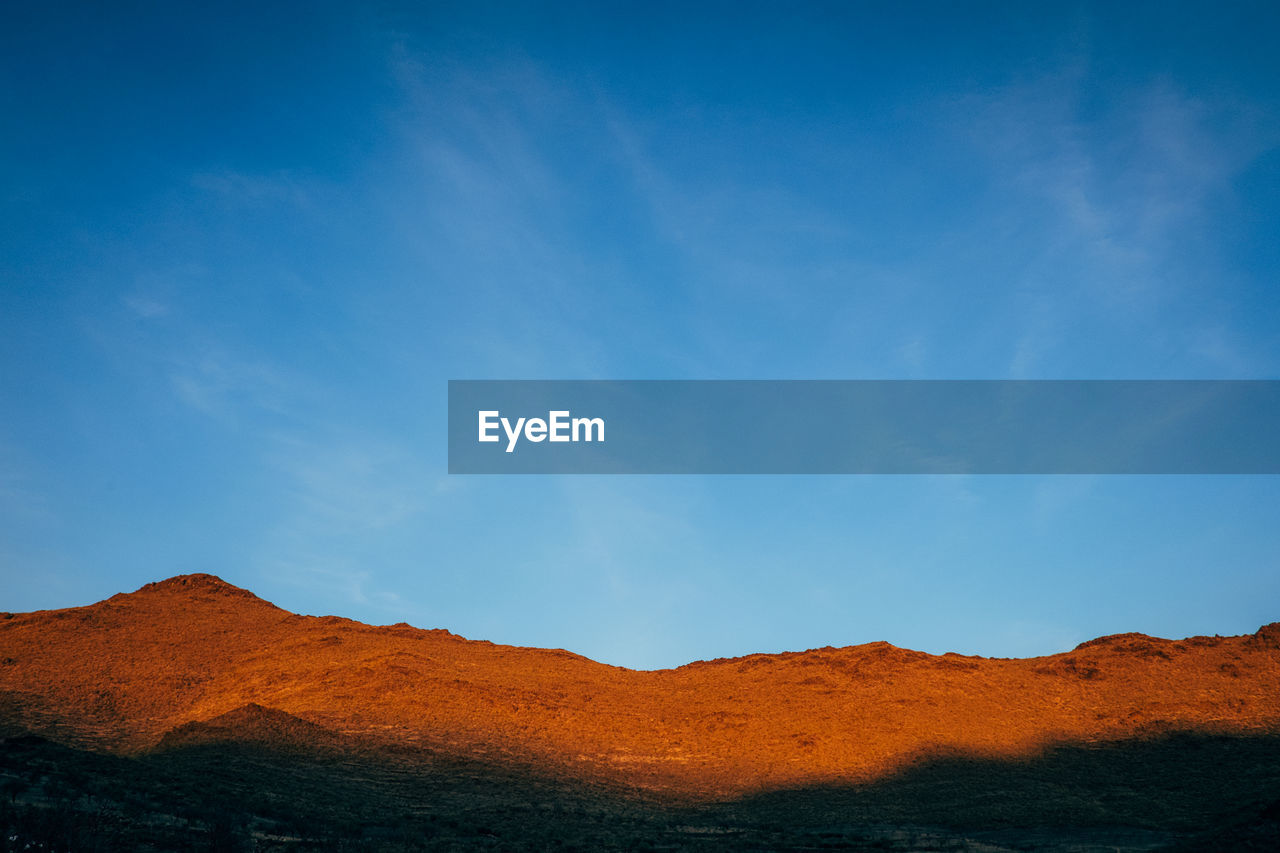 Scenic view of mountains against blue sky