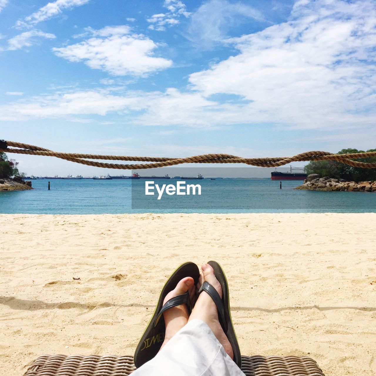 Close-up low section of legs relaxing on beach