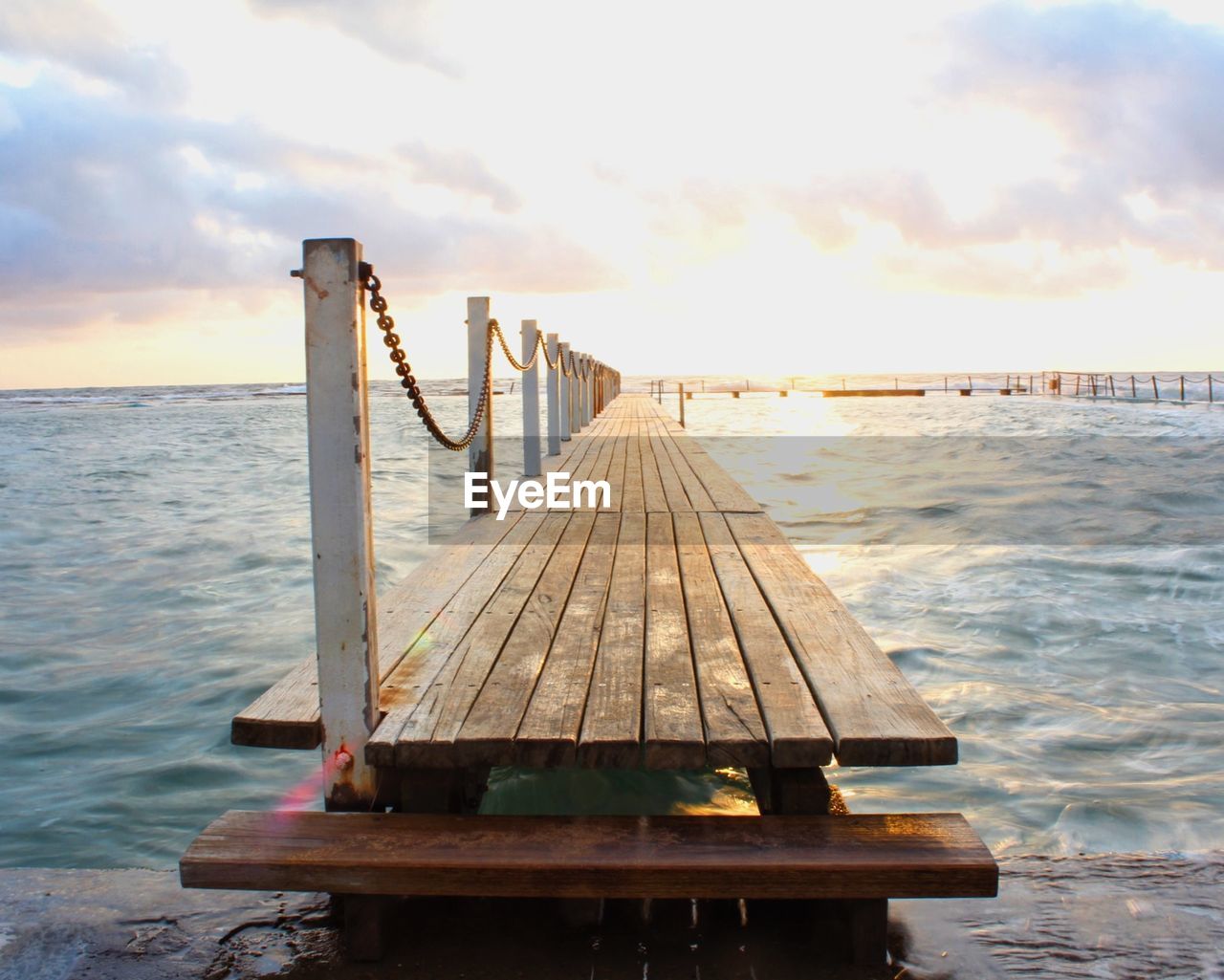 Pier over sea against sky during sunset