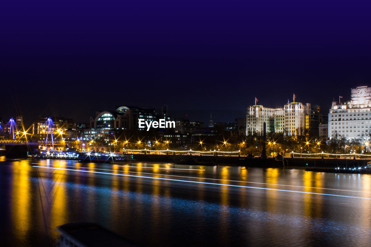 Light trail over thames river against sky