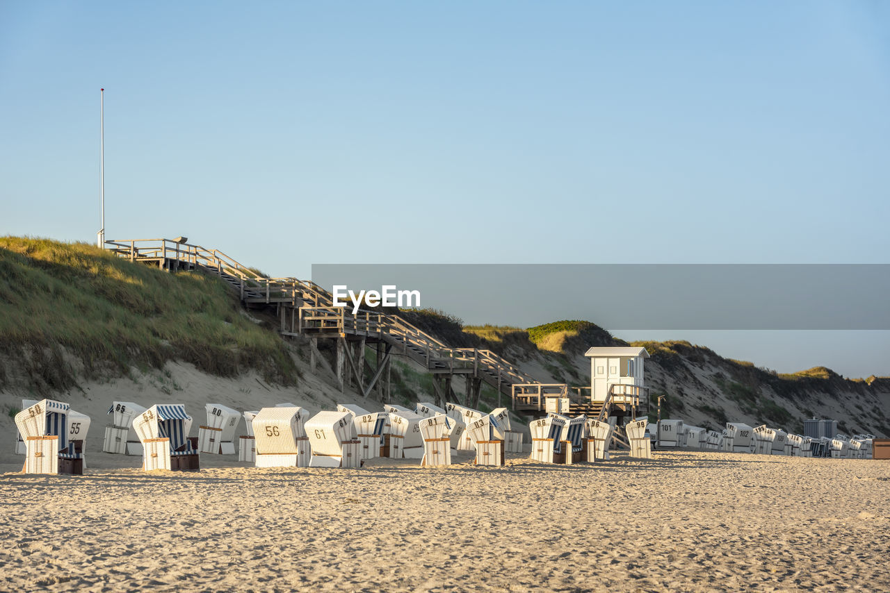 Hooded chair on beach against sky