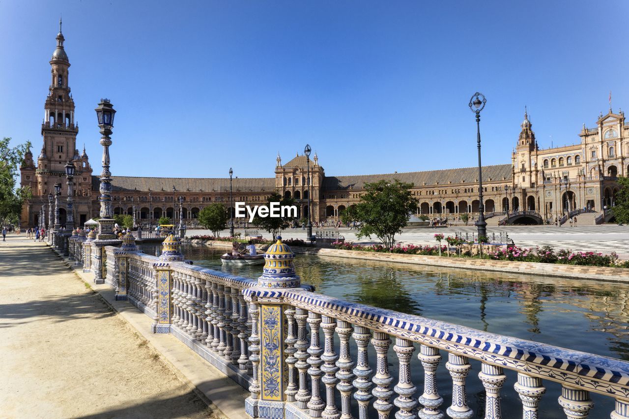 View of buildings by river against clear sky