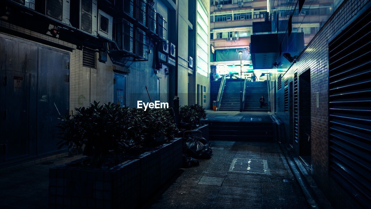 Walkway amidst buildings in city at night