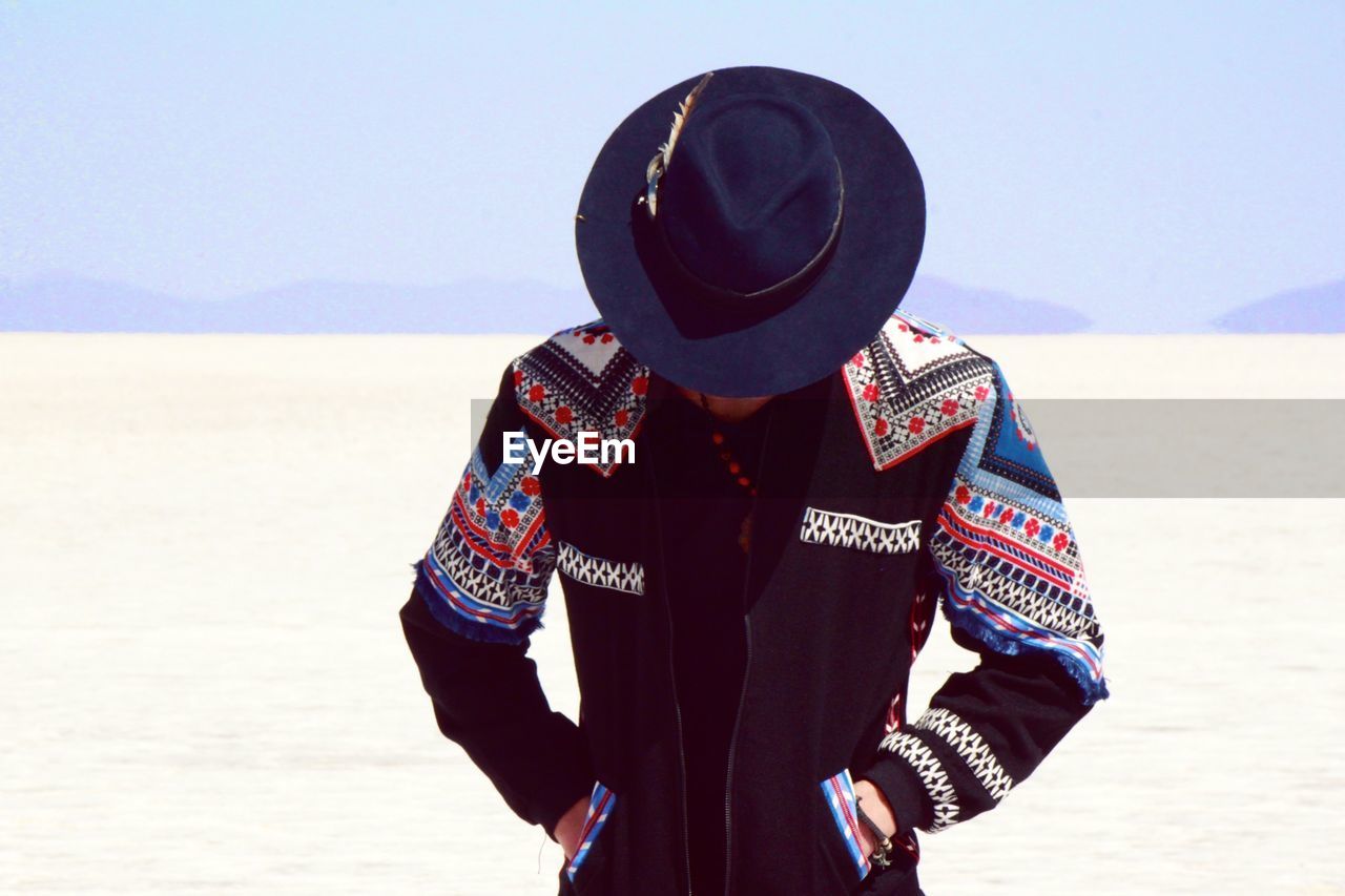 Man looking down wearing hat and costume at salar de uyuni