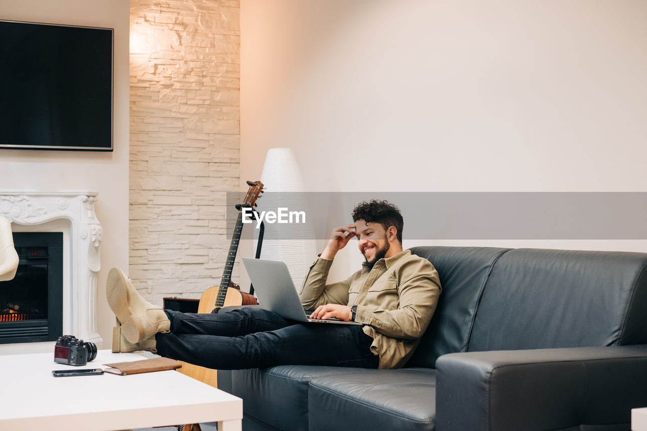 Man using mobile phone while sitting on sofa at home