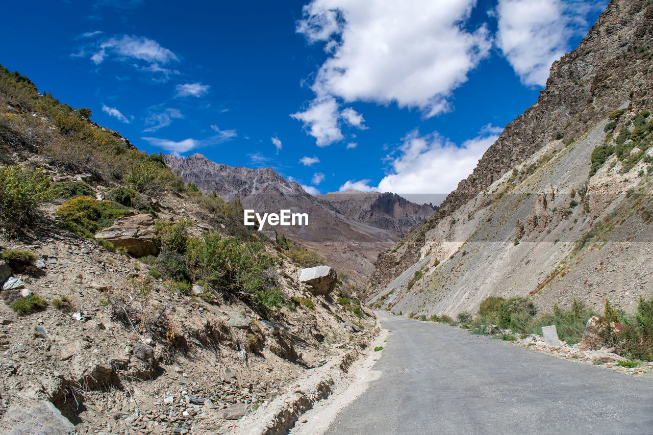 ROAD AMIDST MOUNTAINS AGAINST BLUE SKY