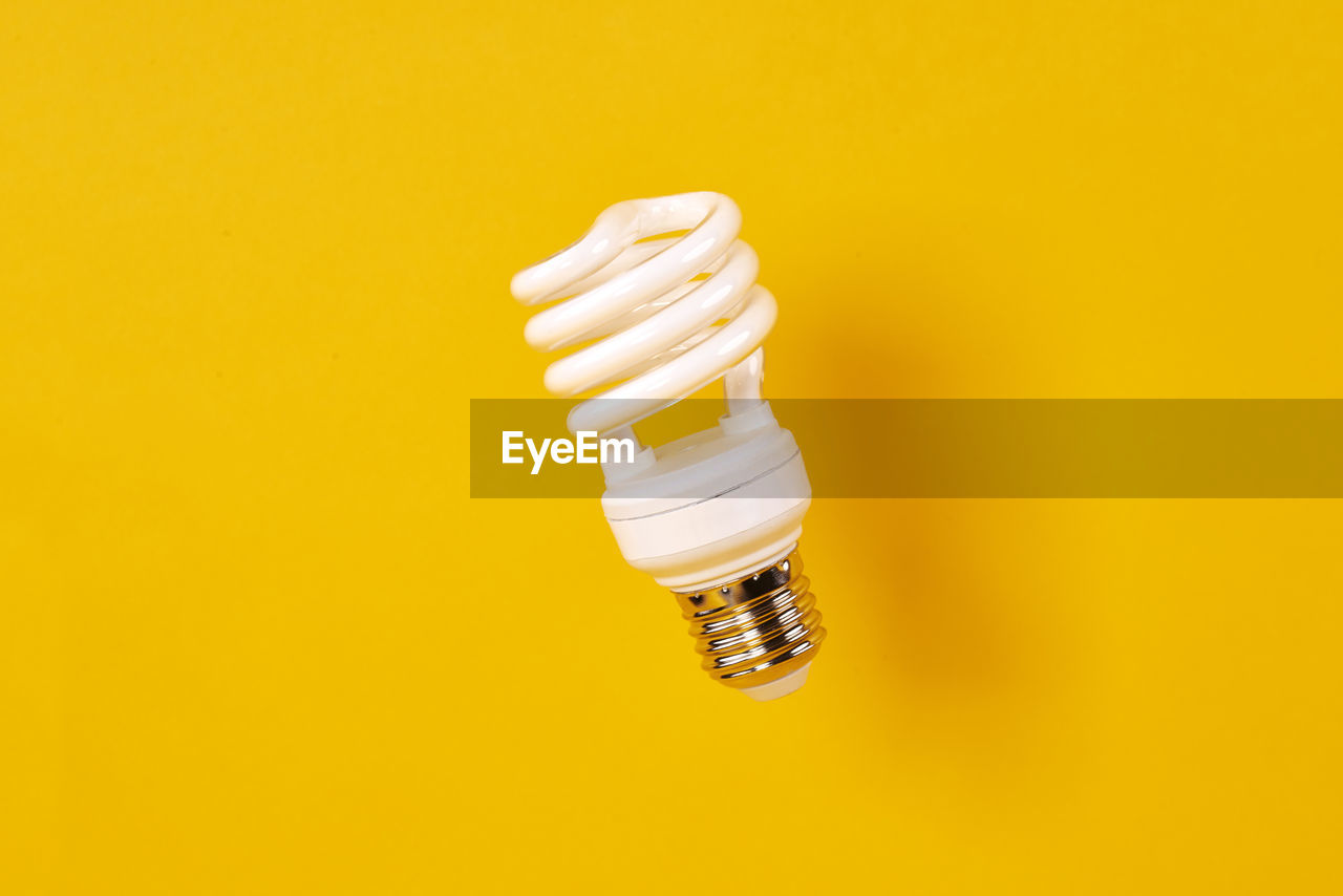 Close-up of light bulb over yellow background