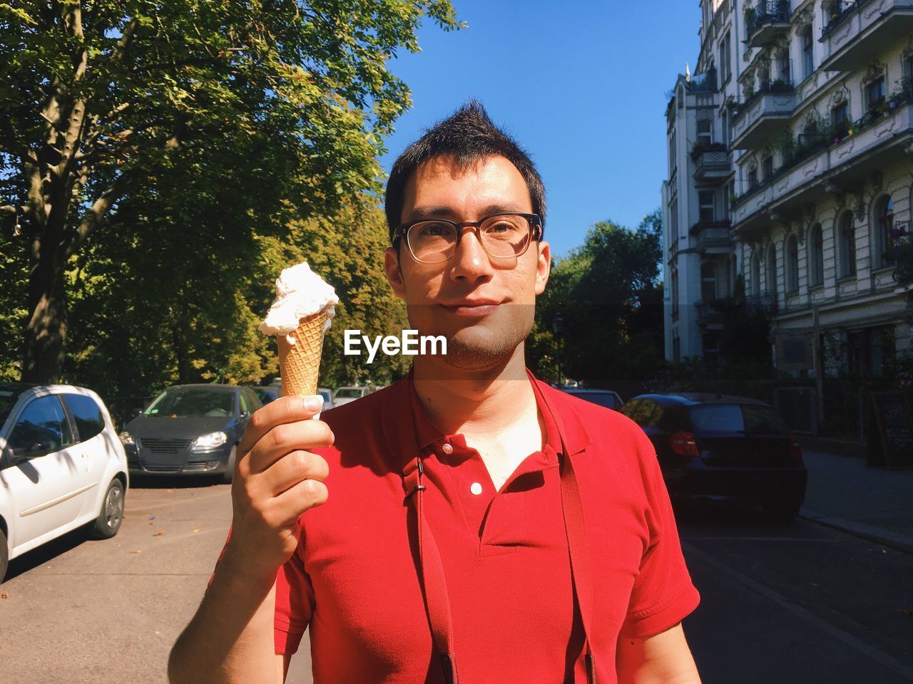 Portrait of young man holding ice cream cone on street