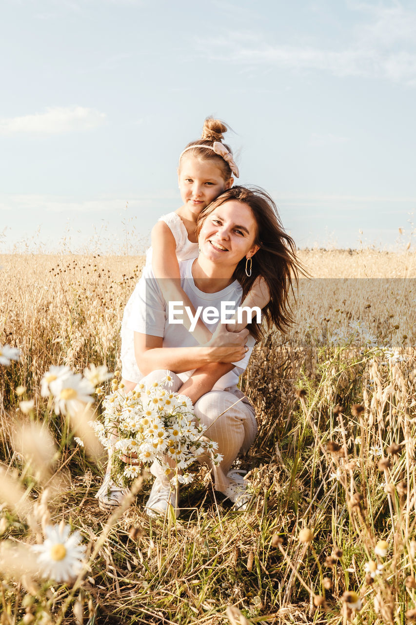 PORTRAIT OF SMILING YOUNG WOMAN ON FIELD