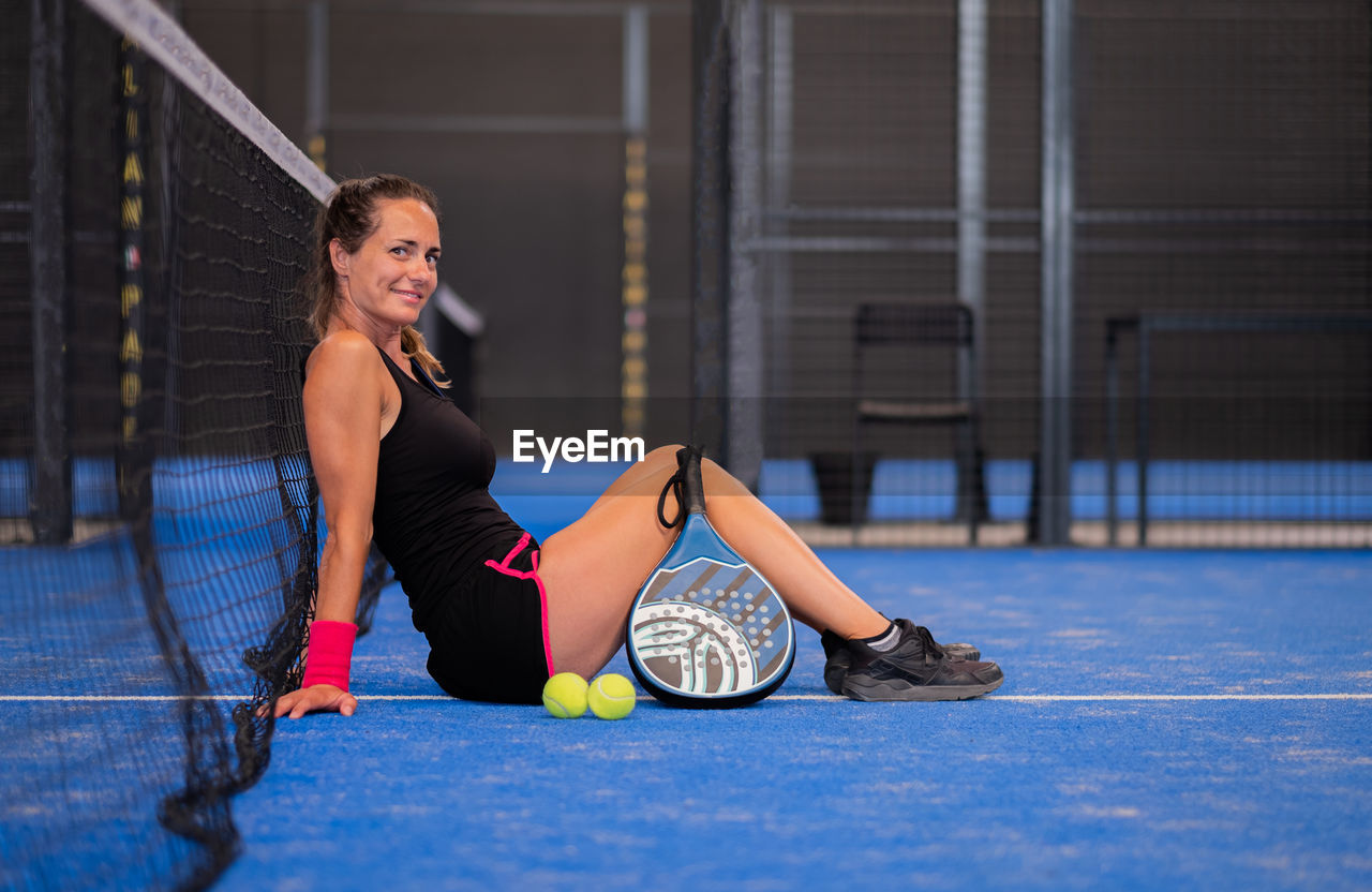 Portrait of beautiful woman playing padel tennis court indoor