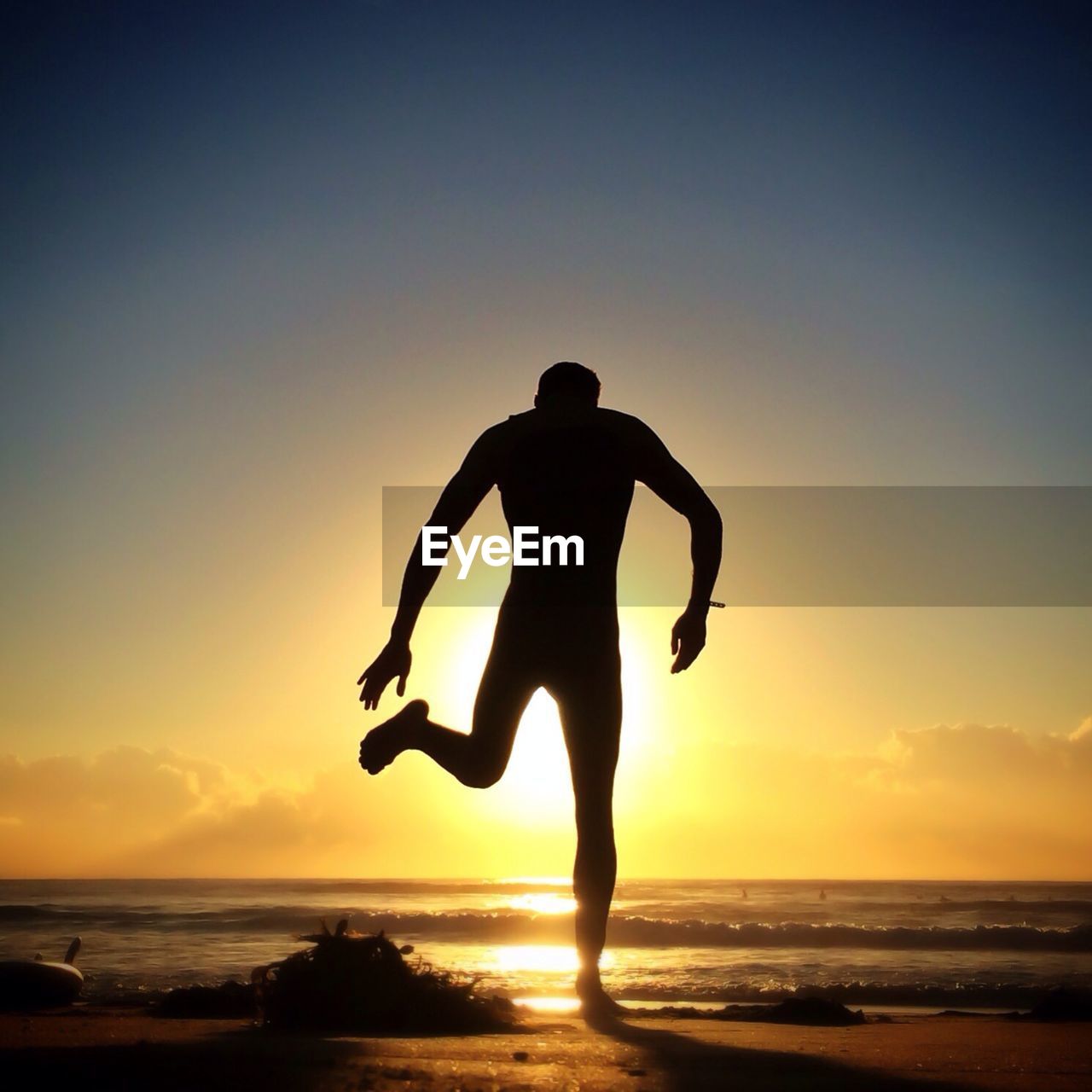 Silhouette man standing on beach at sunset