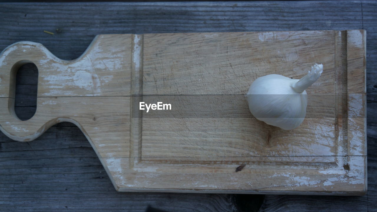 High angle view of garlic on wooden cutting board on wooden table