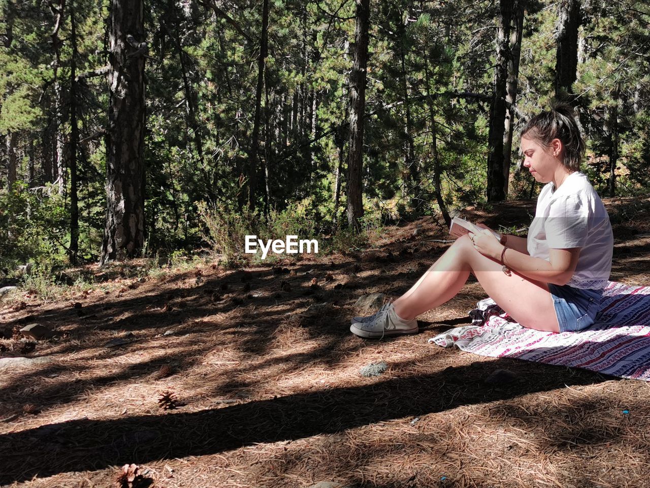 Young woman reading a book in the forest