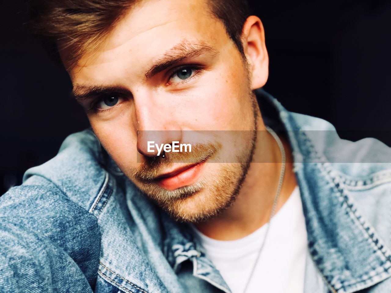 Portrait of young man against black background