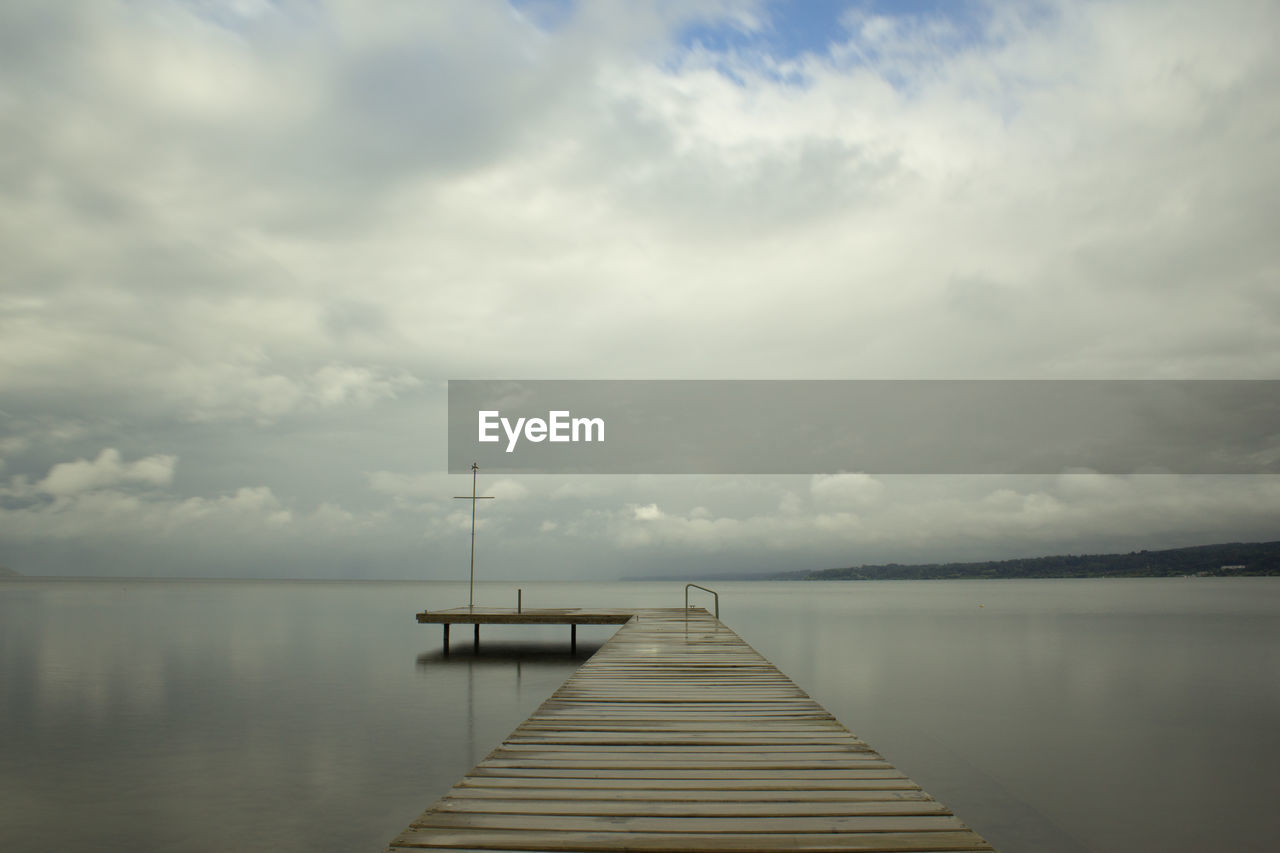 Pier on sea against cloudy sky