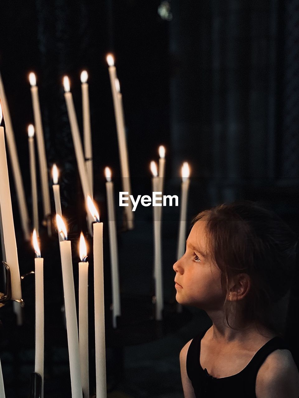 Girl looking at the candles with a hope in the eyes 