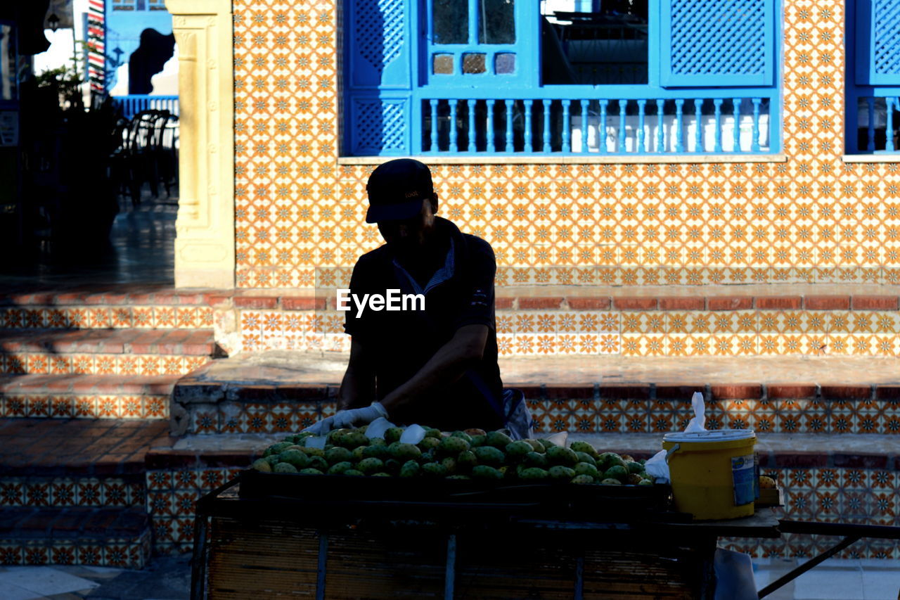 FULL LENGTH OF MAN SITTING IN ILLUMINATED CITY