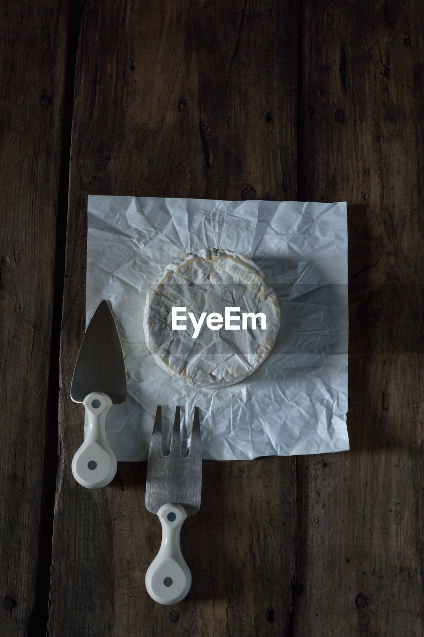 Camembert cheese with cheese fork and cheese knife on wooden rustic table