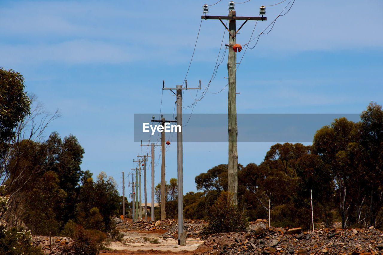 technology, tree, sky, electricity, nature, cable, plant, power generation, electricity pylon, overhead power line, tower, no people, power supply, day, power line, land, outdoors, communication, cloud, mast, architecture, transmission tower, landscape, blue, outdoor structure, low angle view, environment