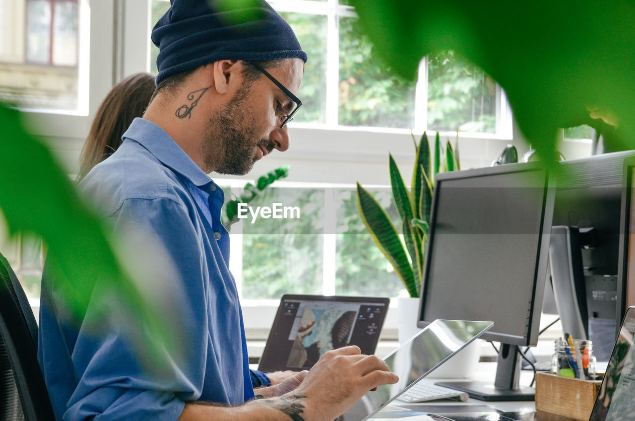 Side view of man using digital tablet in office