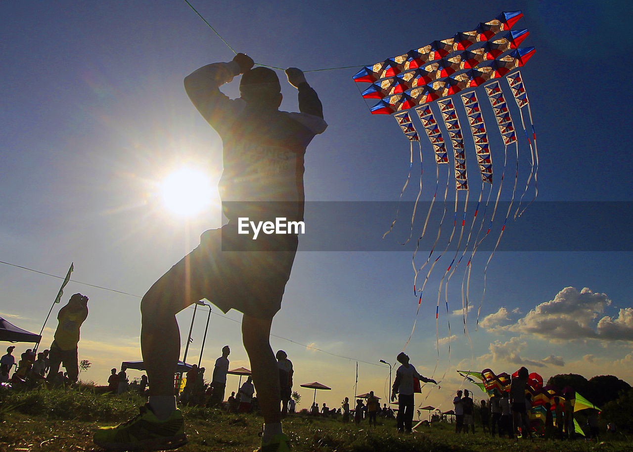 WOMAN WITH UMBRELLA AGAINST SKY AT SUNSET