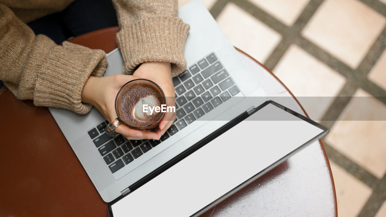 cropped hand of woman using laptop on table