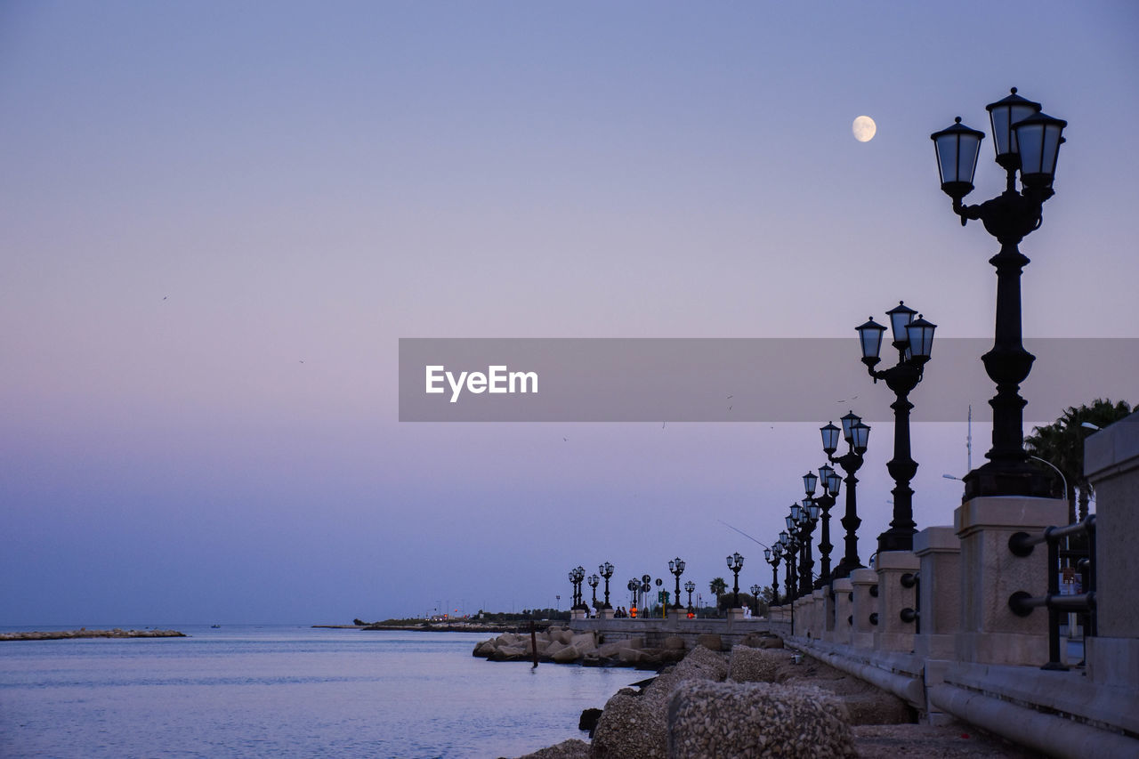 Street light by sea against clear sky at dusk