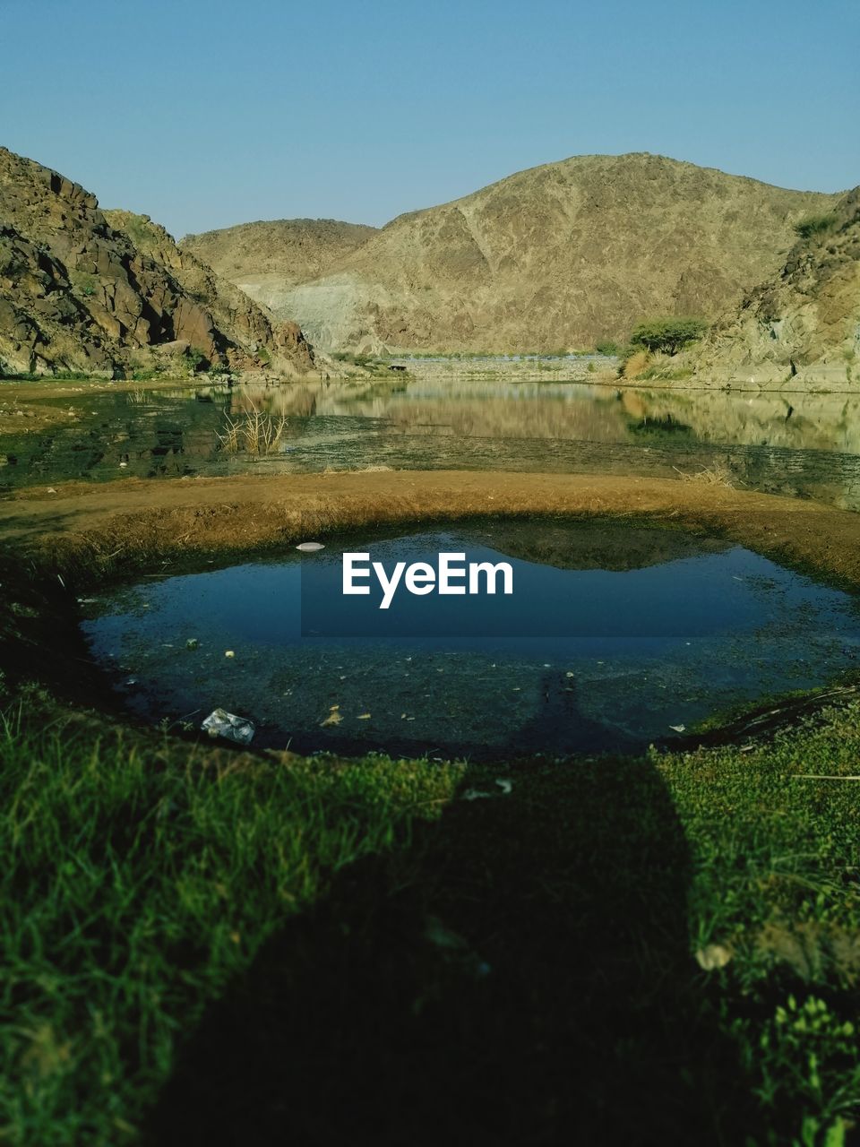 Scenic view of lake and mountains against clear blue sky