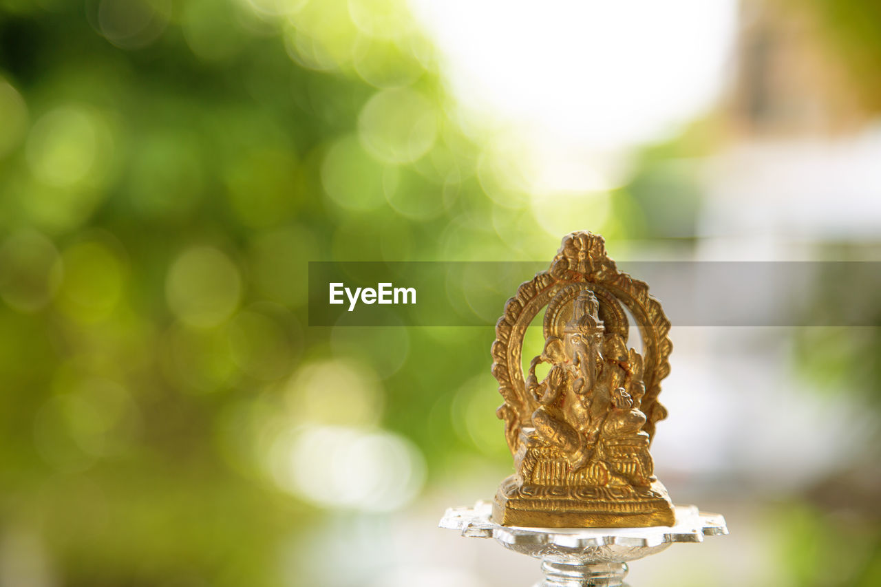 yellow, green, macro photography, religion, no people, gold, focus on foreground, close-up, nature, spirituality, belief, outdoors, leaf, selective focus, flower, decoration, plant, craft, day, animal, lighting