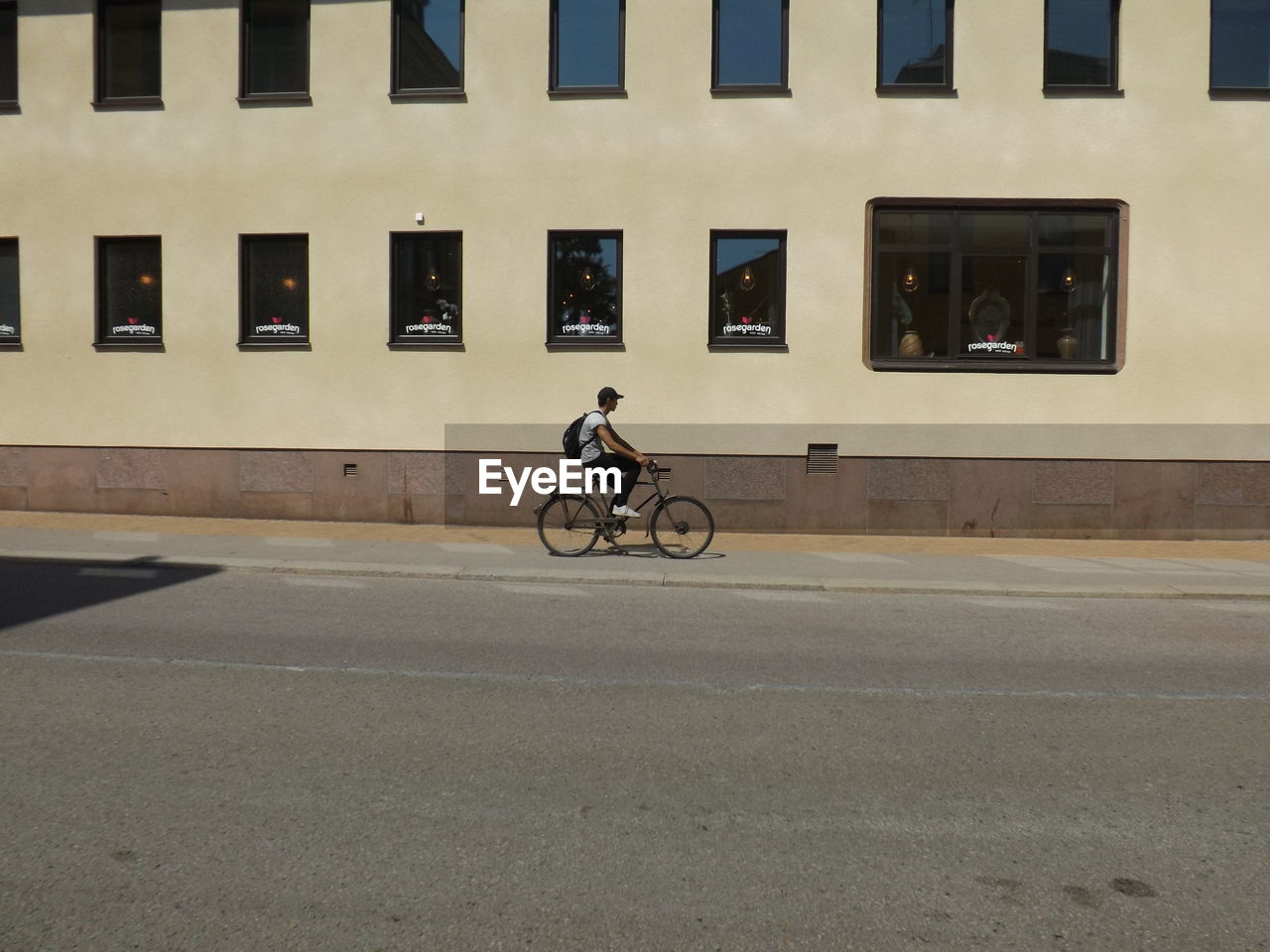 MAN RIDING BICYCLE ON STREET AGAINST BUILDING