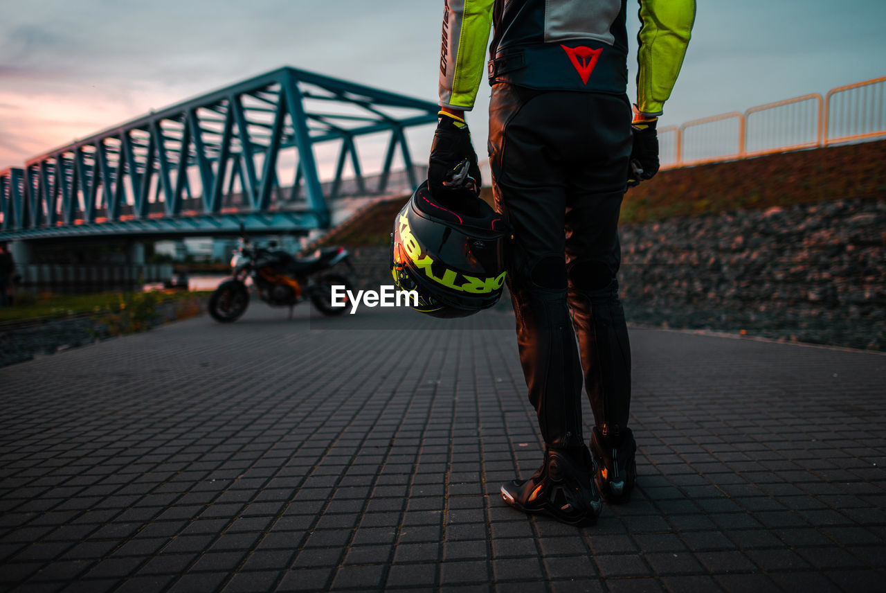 REAR VIEW OF MEN WALKING ON BRIDGE