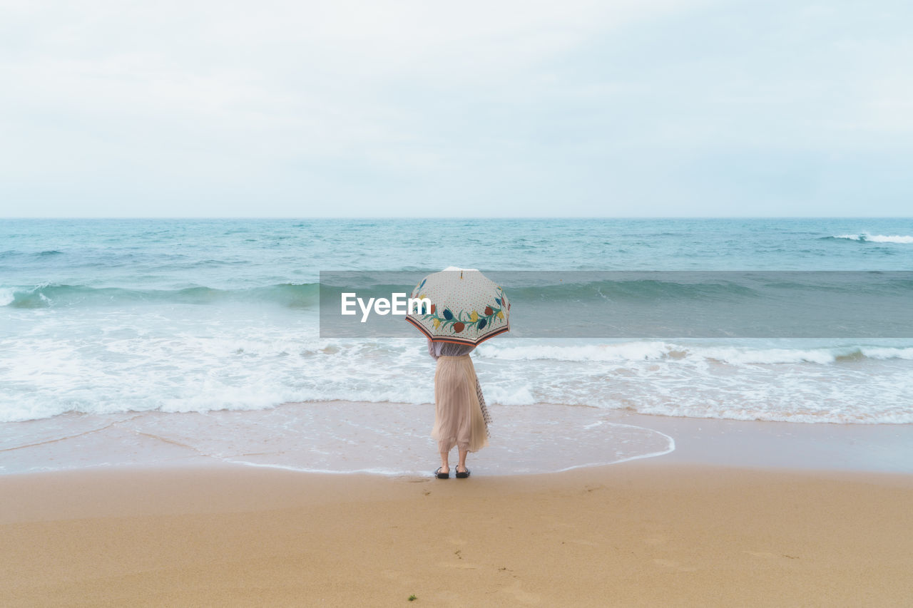 rear view of woman standing at beach