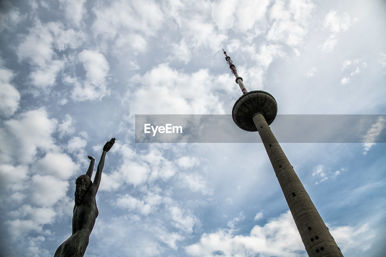 Low angle view of communications tower against cloudy sky