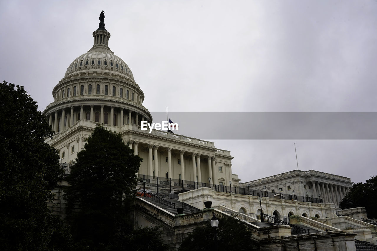 View of the senate capitol building during cloudy day, american flag half mast, washington dc, usa