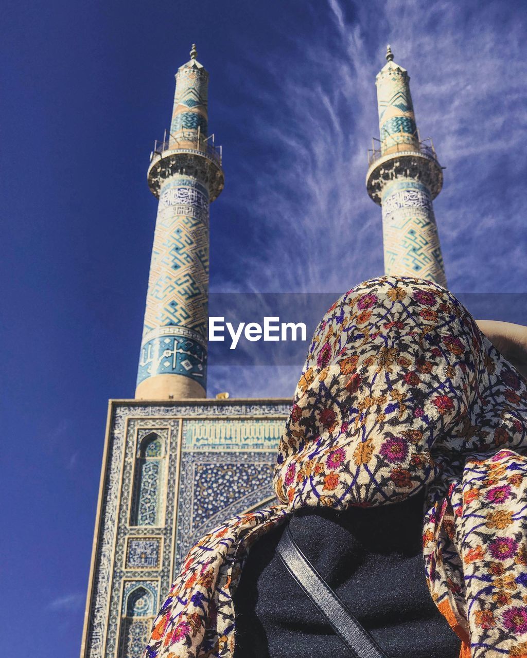 Low angle view of woman and mosque against blue sky