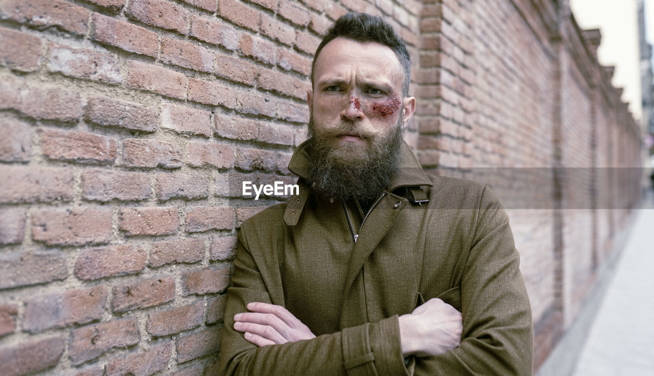 Hipster man with beard and cinema makeup posing on the street and looking at camera