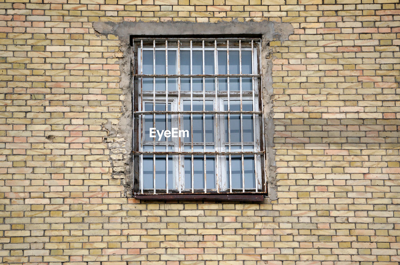 LOW ANGLE VIEW OF WINDOW ON BRICK WALL OF HOUSE