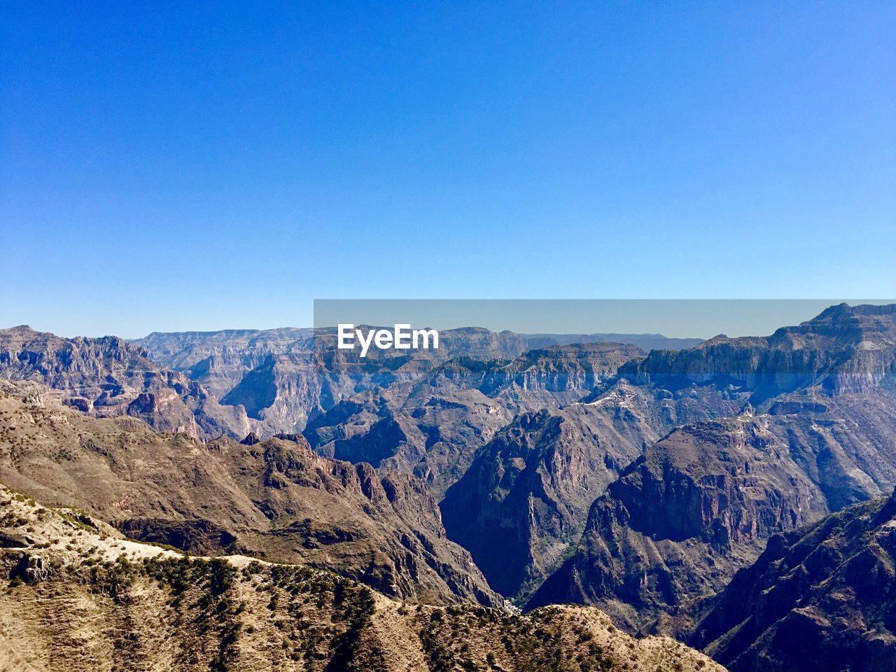 Panoramic view of mountains against clear blue sky