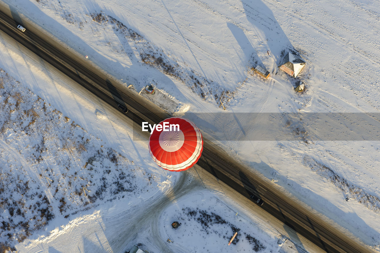 Hot air balloon flying over snow covered field