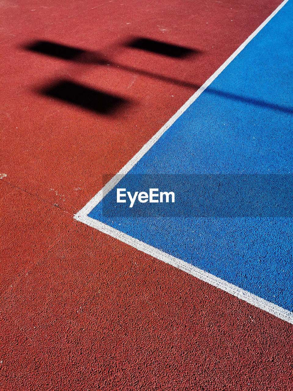 HIGH ANGLE VIEW OF BASKETBALL HOOP IN BLUE SHADOW