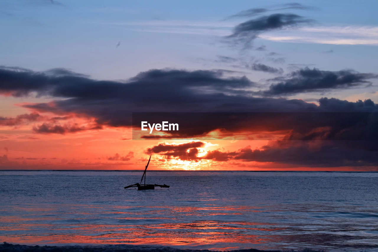 Silhouette sailboat in sea against sky during sunset