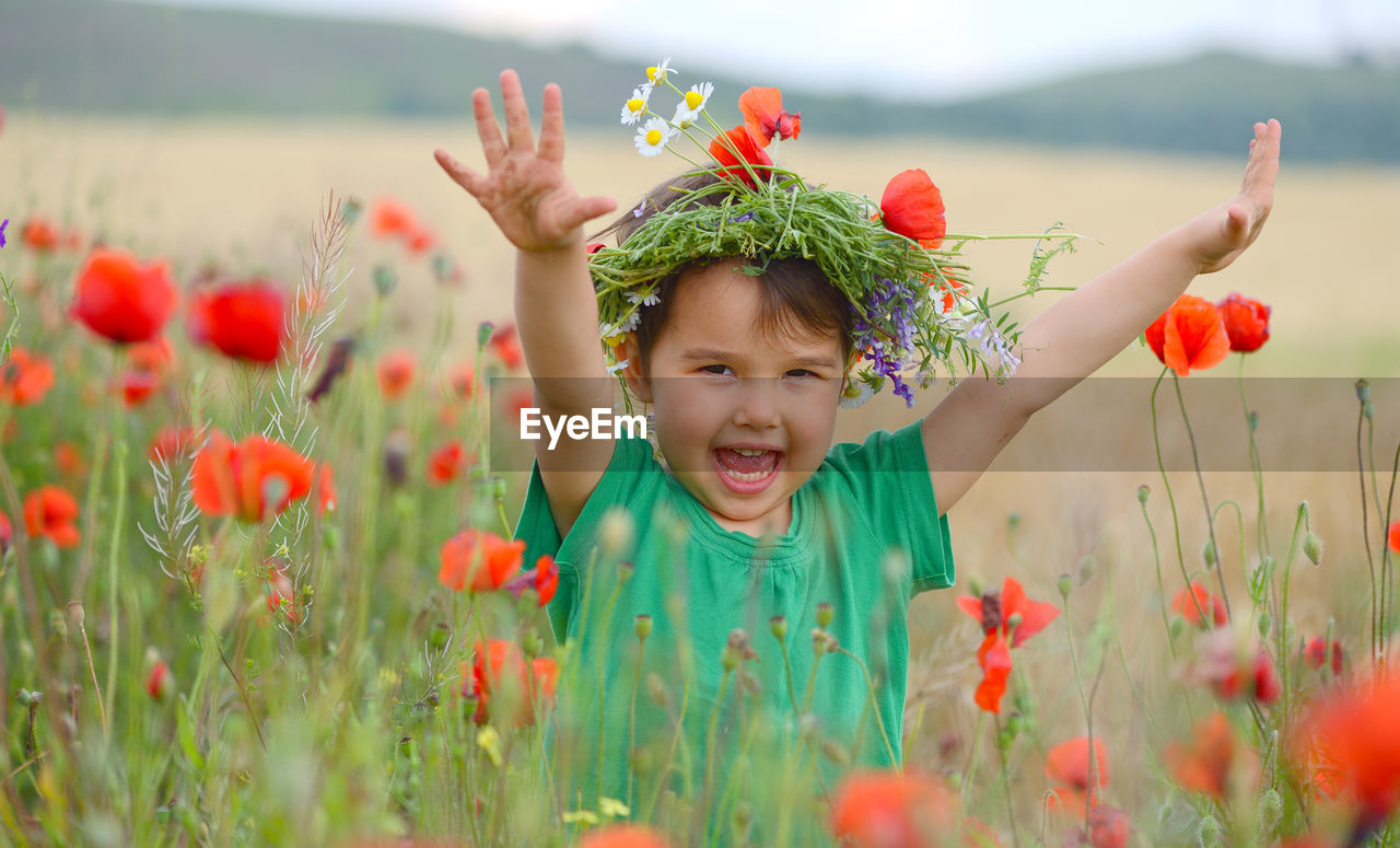 PORTRAIT OF HAPPY GIRL WITH FLOWERS ON FIELD AT HOME