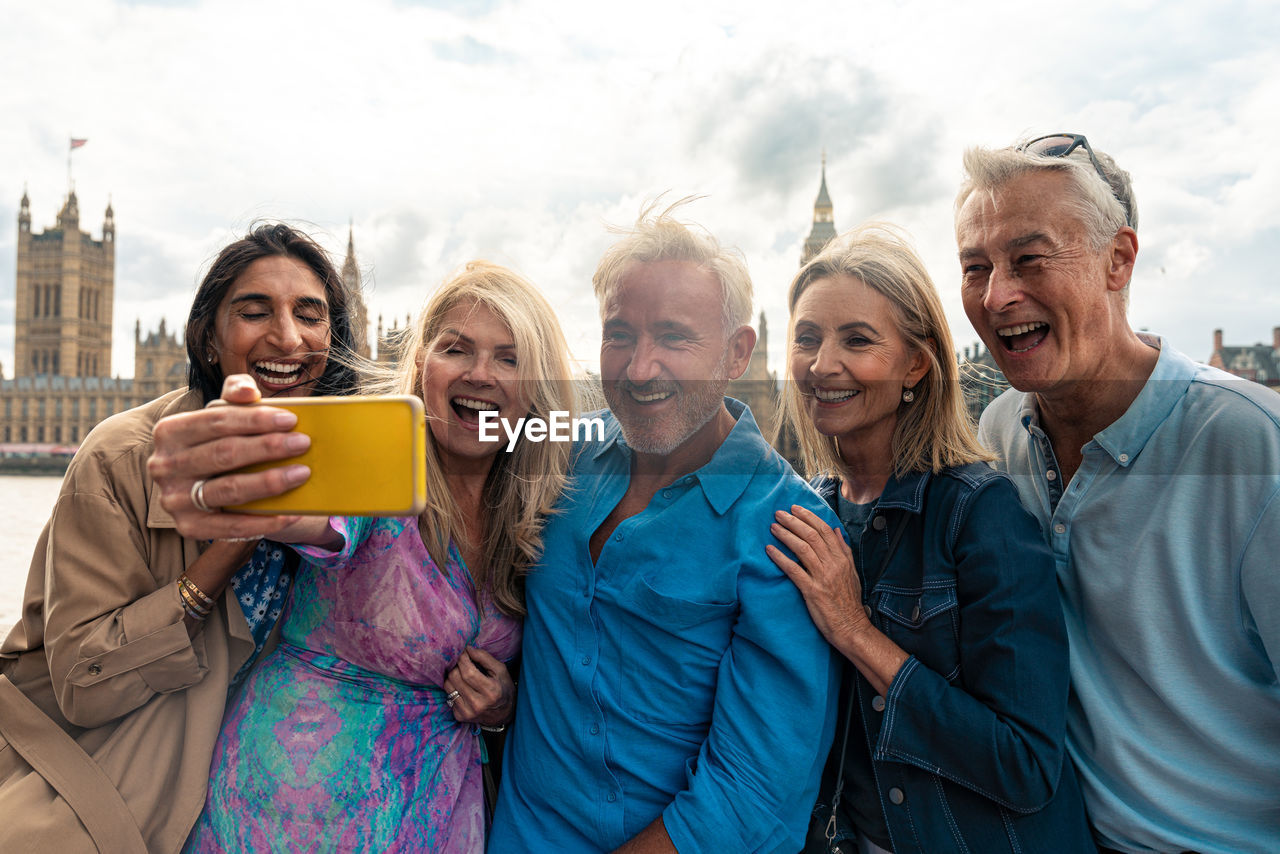 portrait of smiling friends standing against the sky