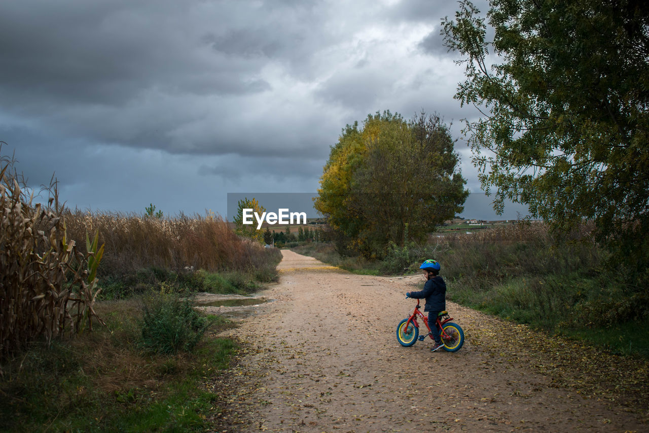 Man riding bicycle on field against sky