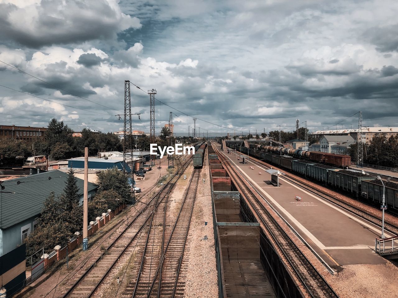 HIGH ANGLE VIEW OF RAILROAD STATION AGAINST CLOUDY SKY