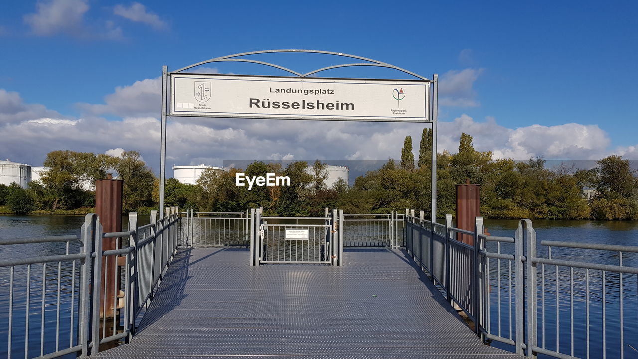 INFORMATION SIGN BY RAILING AGAINST TREES