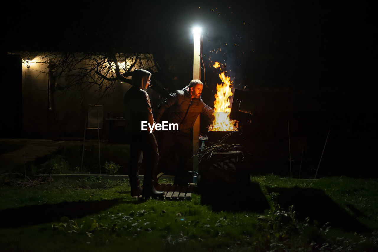 A father and son build a barbecue fire on their plot to cook dinner on an open fire. 