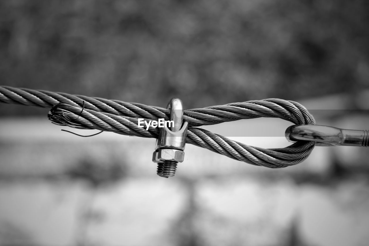 CLOSE-UP OF ROPE HANGING ON METAL