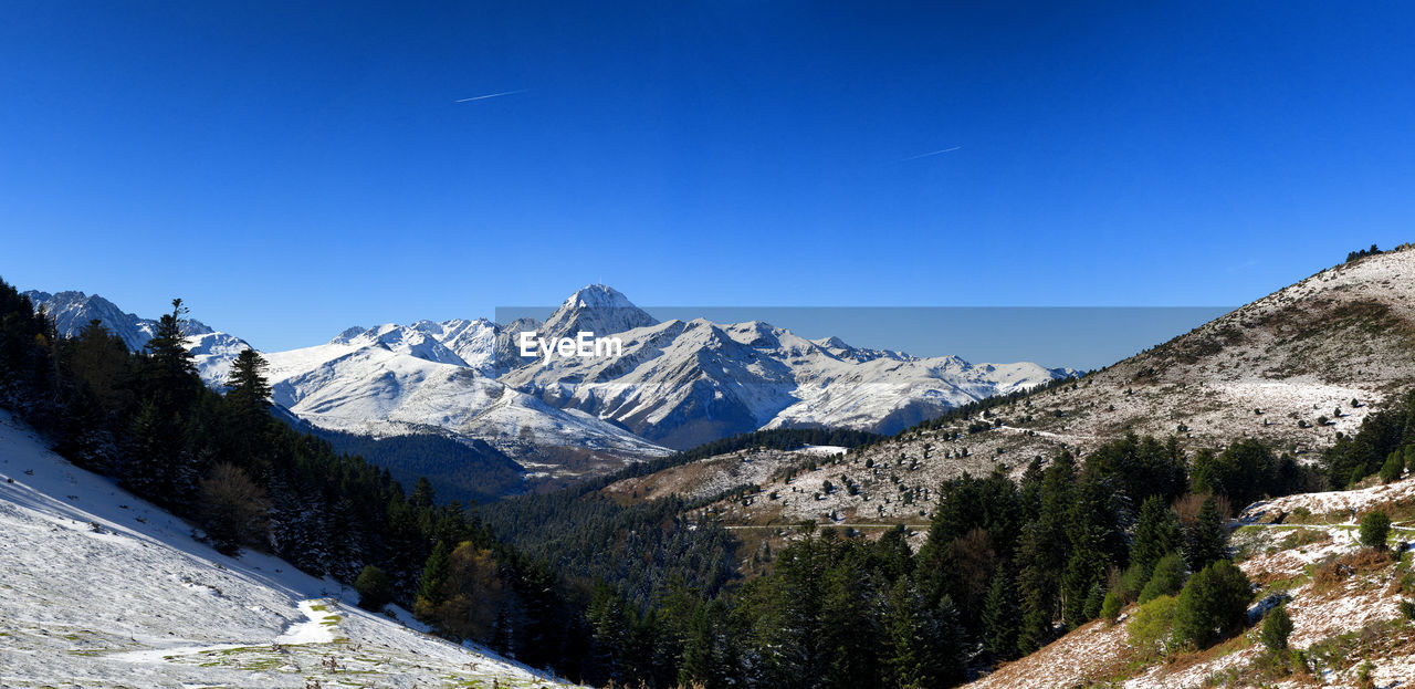 Scenic view of snowcapped mountains against clear blue sky